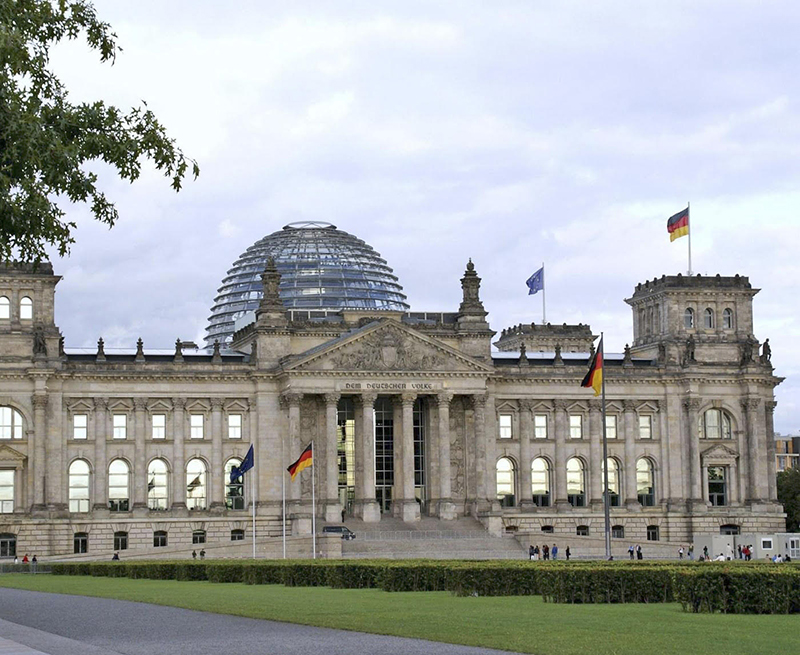ドイツ国会議事堂（通称ライヒスターク）　ドイツ帝国議会議事堂として１８８２年コンペで選ばれ１８９４年竣工。設計パウル・ヴィロット。１９３３年失火により全焼。その後１９４３年のベルリン空襲で壁面のみ残し半壊。１９９２年修復コンペで、外国人、イギリスのノーマン・フォスター案が選ばれる。ドイツ再統一のシンボルとして１９９９年に竣工。