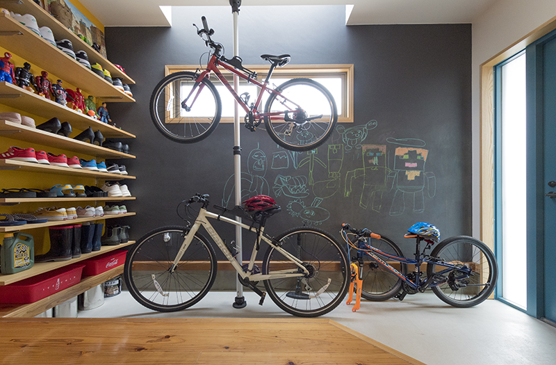 広さ約４畳の土間の玄関。一家で楽しむサイクリングの自転車を飾りながら収納でき、メンテナンスもできる。壁の一面は黒板になっており、２人の子どもたちはお絵かきを楽しむ
