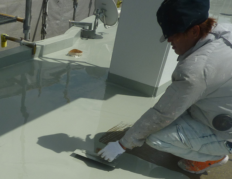屋上への防水塗装の作業風景。塗料の機能を最大限引き出せるよう、職人が丁寧に仕上げていく