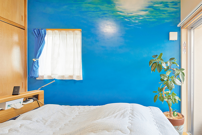 ２階寝室。壁面は夫人の好きな沖縄の海をイメージして、夫婦の友人がスプレーアートで描いた。夫人は「海の底で眠っているような気分になる」