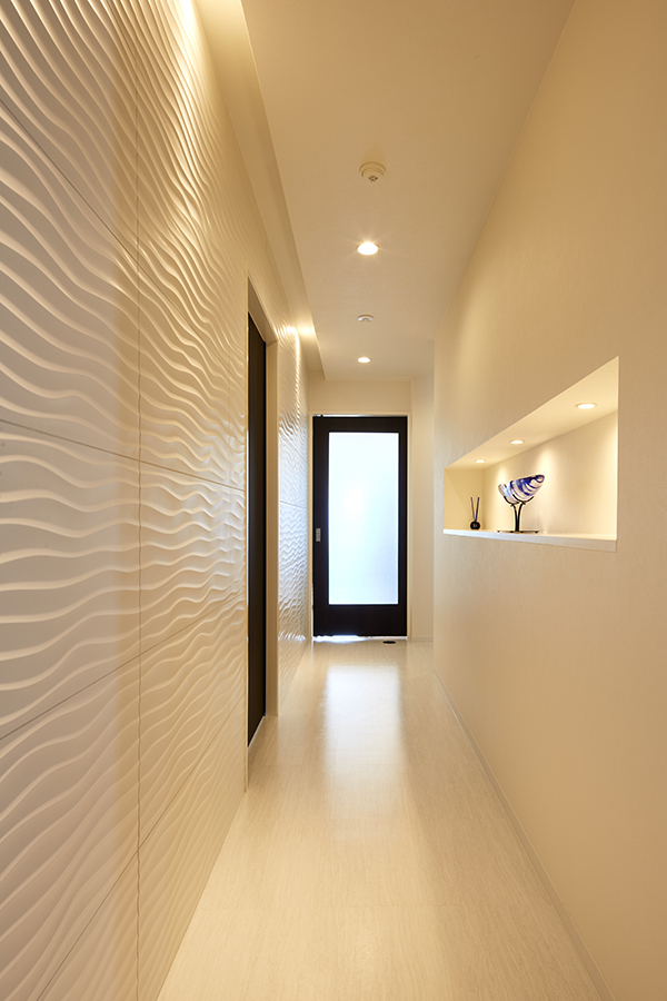 壁を波模様のタイル仕上げにした廊下は、間接照明を生かしたギャラリースペース