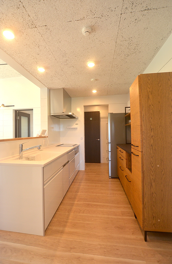 対面式キッチンも白で統一して爽やかに。写真奥の出入り口から、水回りと玄関へ抜けることができる