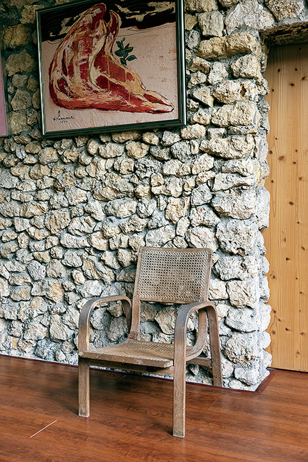 山元恵一さんの描いた作品と、山元さんが座っていたという椅子。壁面の仕上げにベニヤ板が張られていたが、改修工事で撤去して石積みをあらわしにすることで建築当初の姿になっている（撮影：岡本尚文）