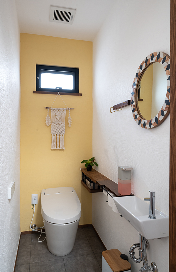 トイレは二つ。細長い敷地の端と端にある。写真は家族が使用する奥のトイレ。黄色のカラー漆喰や鏡などのインテリアにもこだわった夫人お気に入りの空間だ
