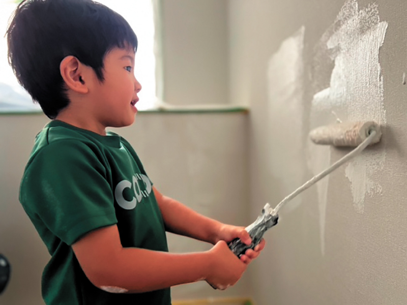 防カビ・抗菌・消臭・調湿効果のある「しっくいペイント（Ｒ）」を塗る子ども。同製品は天然素材なので、安心して使用できる。塗布すると、室内は雨天でもサラッとしていて、涼しく感じるそう