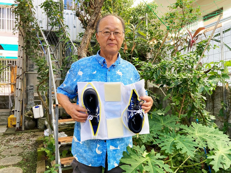 自宅の庭で「靴専用洗濯ネット」をアピールする真渕商会の真境名勝さん